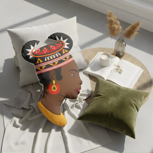a pillow with a stylized profile of a woman's face, along with a green pillow and a vase with dried flowers on a table.