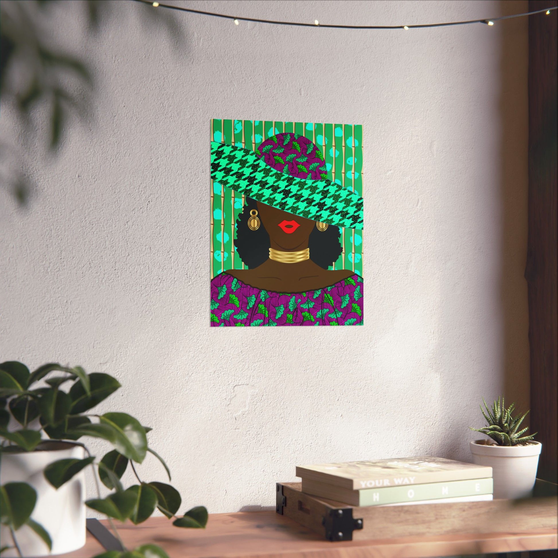a colorful poster of a woman wearing a green and purple patterned hat, displayed on a wall above a wooden table with a stack of books and a potted plant.