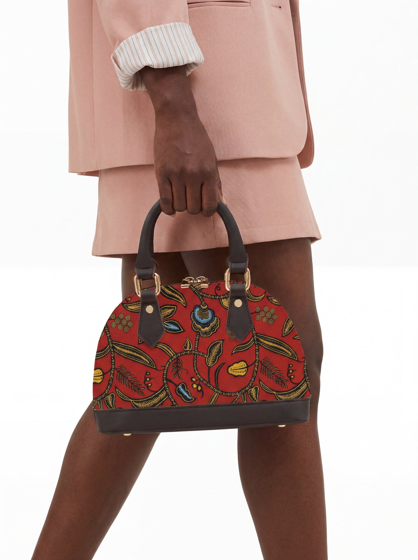 A person is holding a red floral handbag with a black handle.