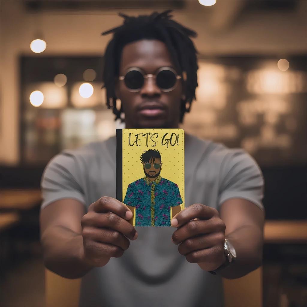 A man holding a yellow notebook with an illustration of a man wearing sunglasses and a colorful shirt, with the text "LET'S GO!" written on it.