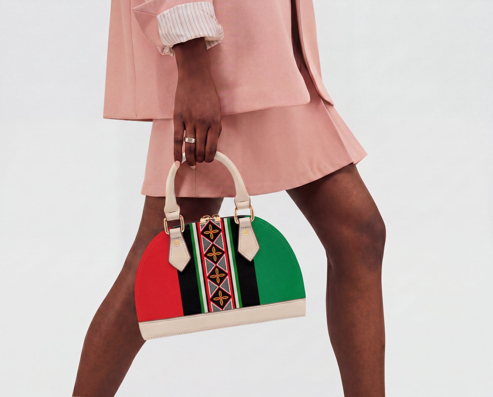A person wearing a pink outfit and holding a colorful handbag stands against a white background.
