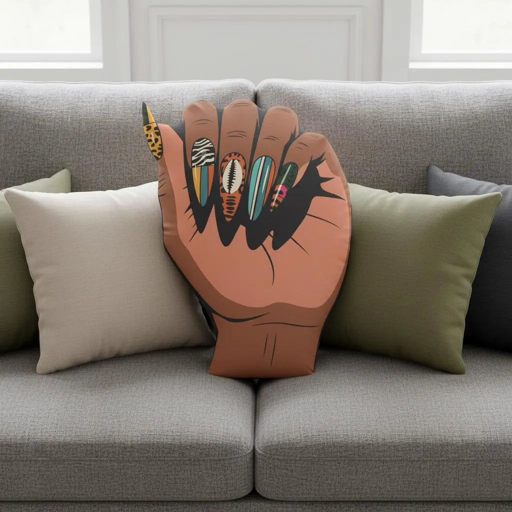 A hand-shaped pillow with colorful nail polish designs is placed on a gray couch.