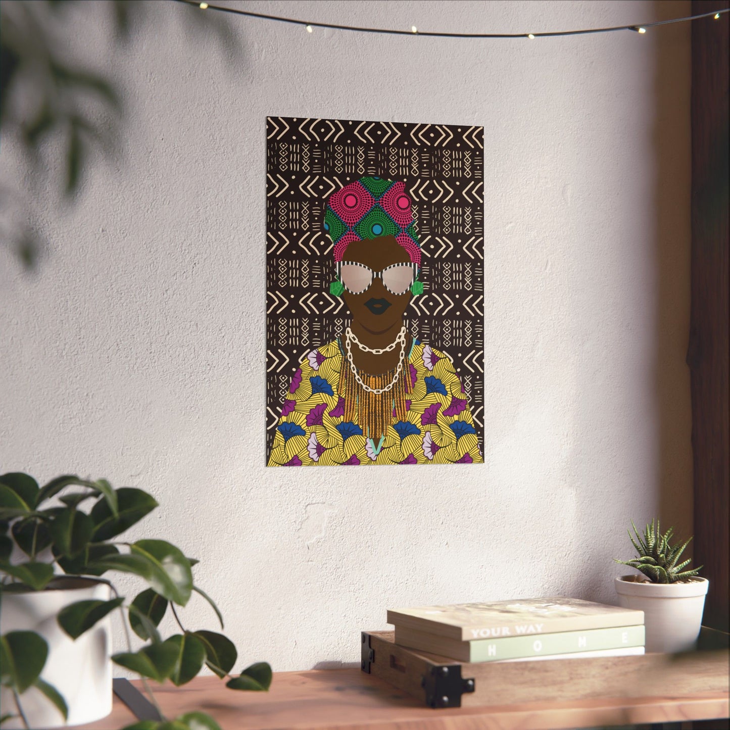a poster of a woman with a colorful, patterned dress hanging on a wall, surrounded by potted plants and a stack of books.