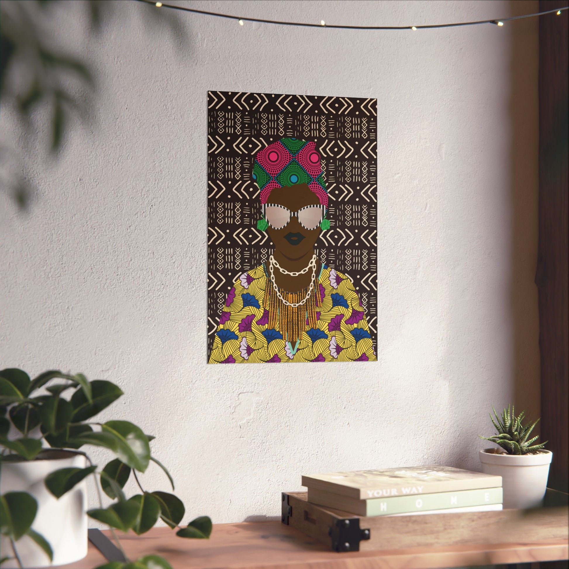 a poster of a woman with a colorful, patterned dress hanging on a wall, surrounded by potted plants and a stack of books.