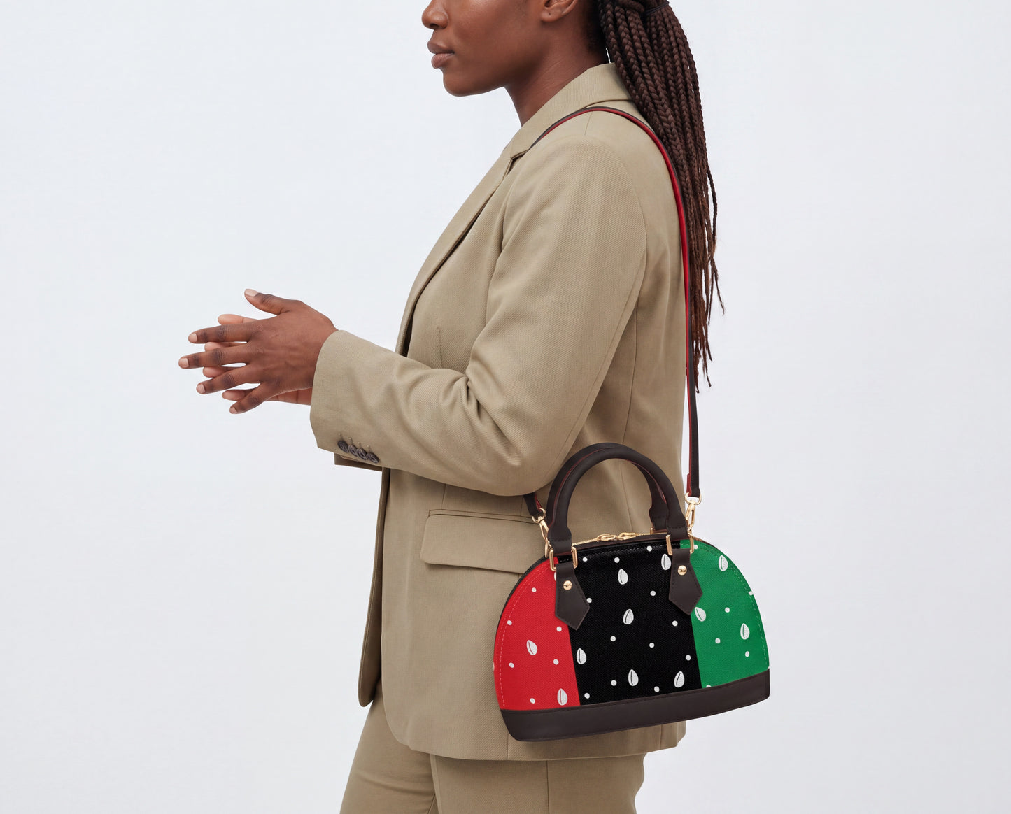 A woman wearing a tan blazer and carrying a colorful handbag with polka dots is standing against a white background.