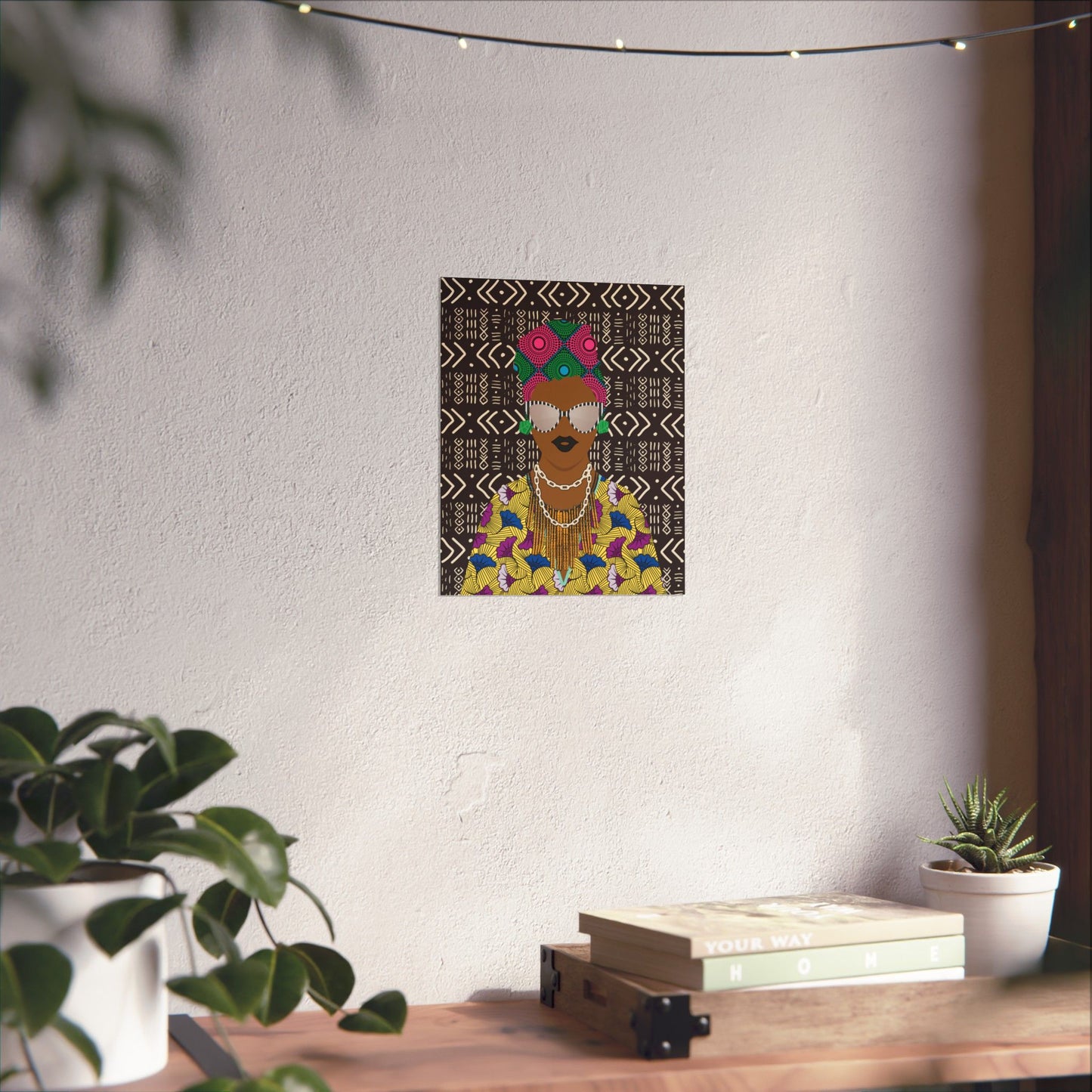 a wall with a framed artwork depicting a colorful, stylized figure wearing a headpiece and a vibrant outfit. The artwork is surrounded by various decorative elements, including potted plants and books, creating a cozy and artistic atmosphere.