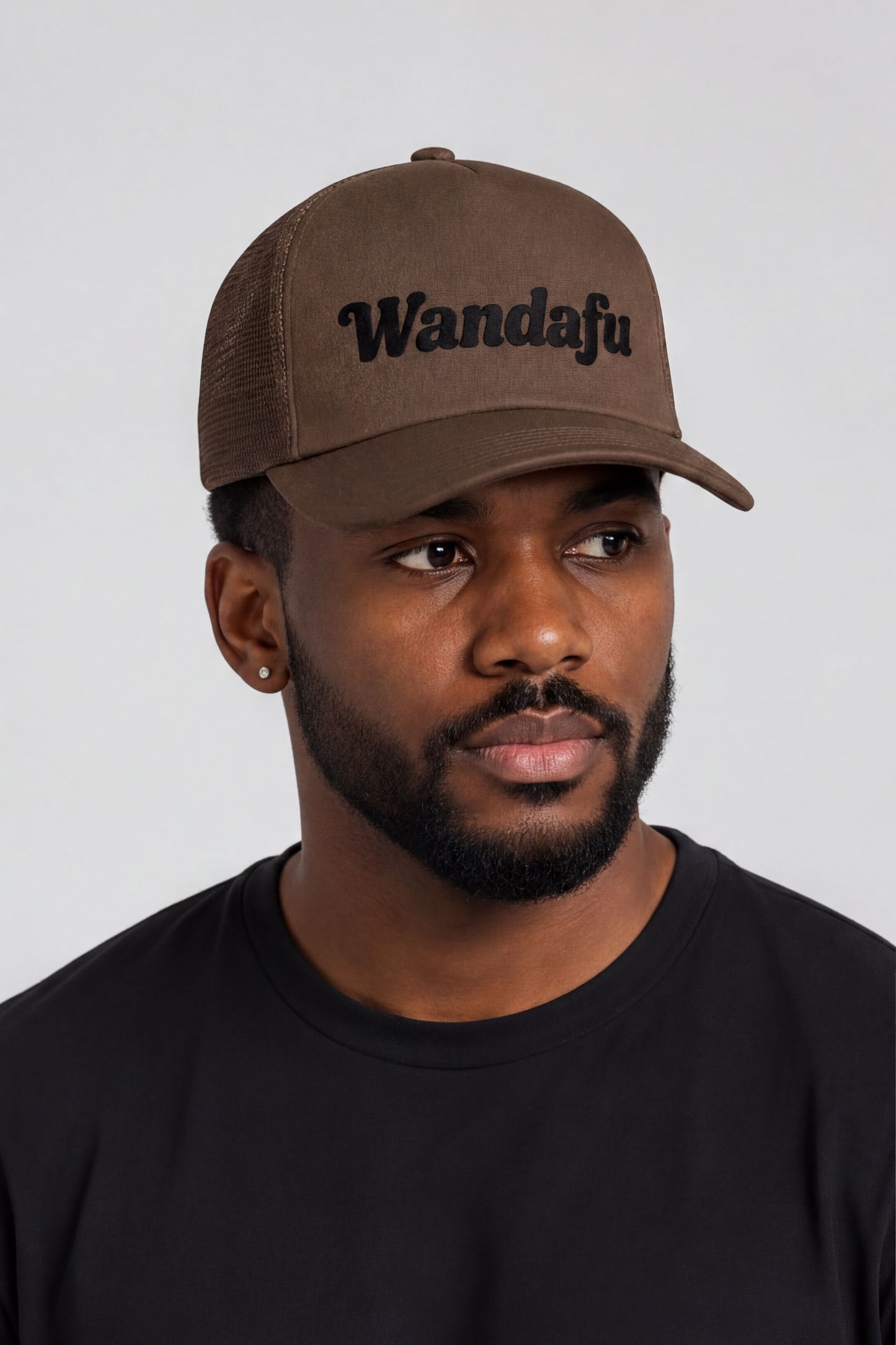 A man wearing a brown baseball cap with the text "Wandafu" printed on it.