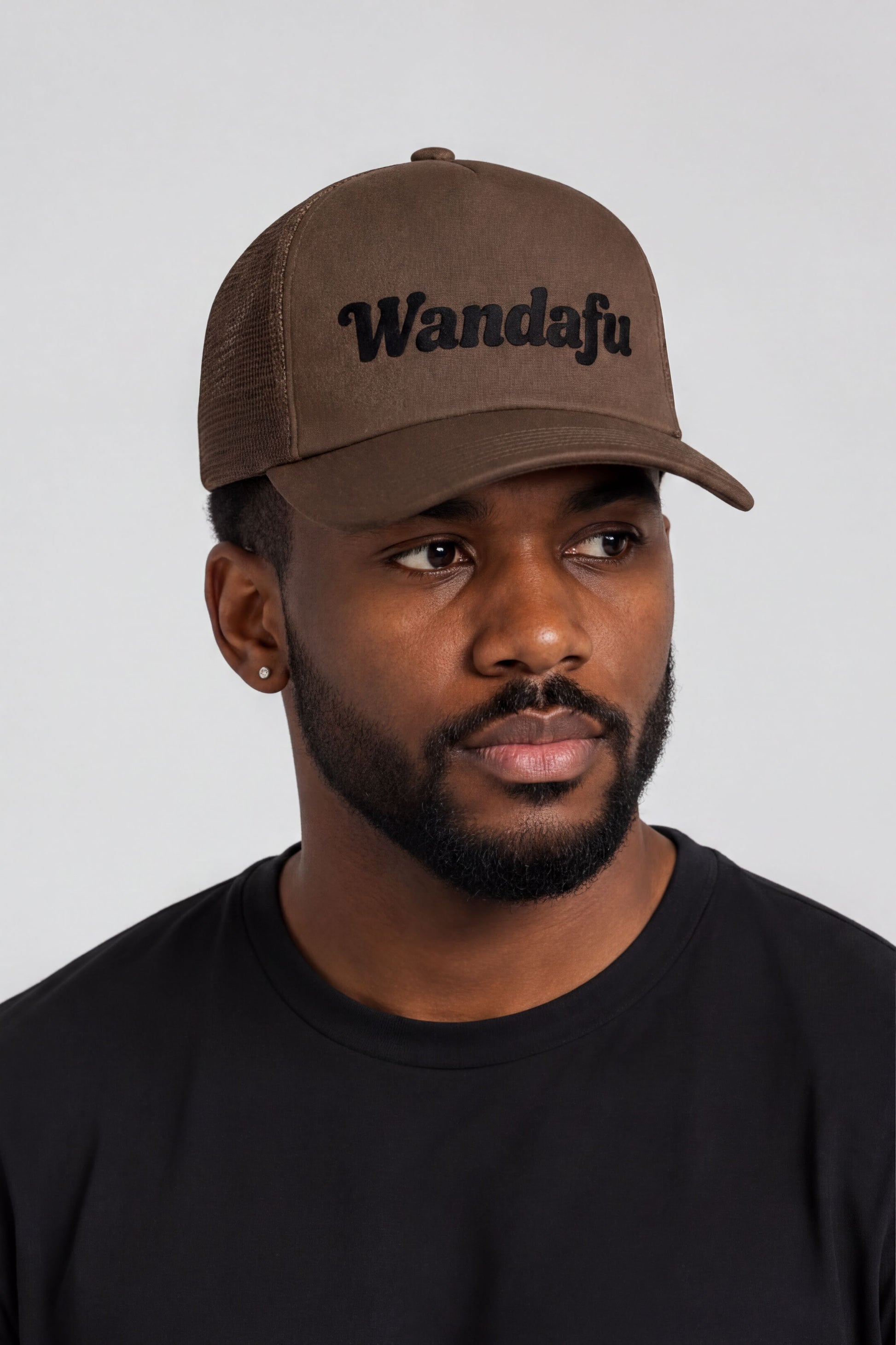 A man wearing a brown baseball cap with the text "Wandafu" printed on it.