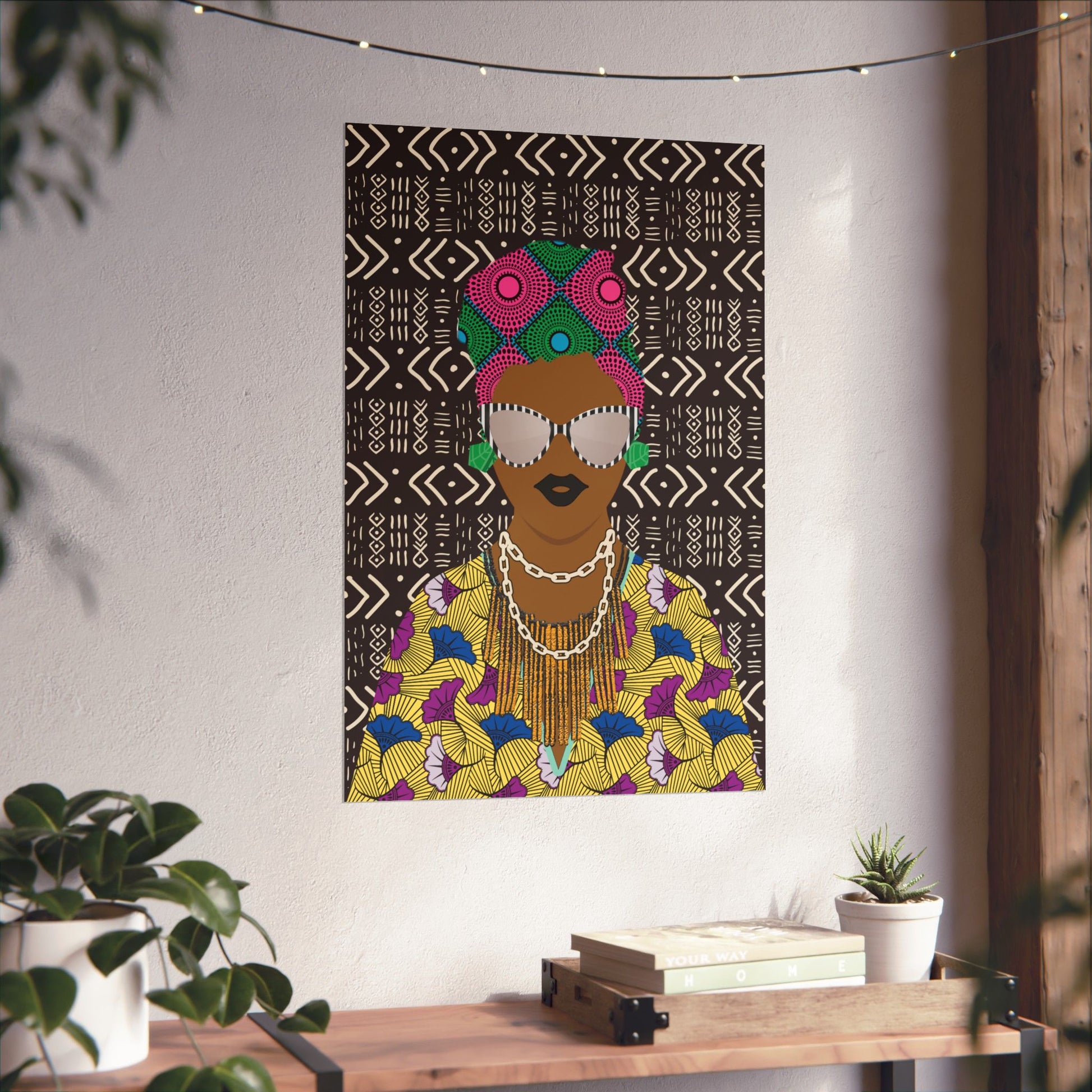 a colorful poster of a woman with a head wrap, displayed on a wall in a room with a wooden table and potted plants.