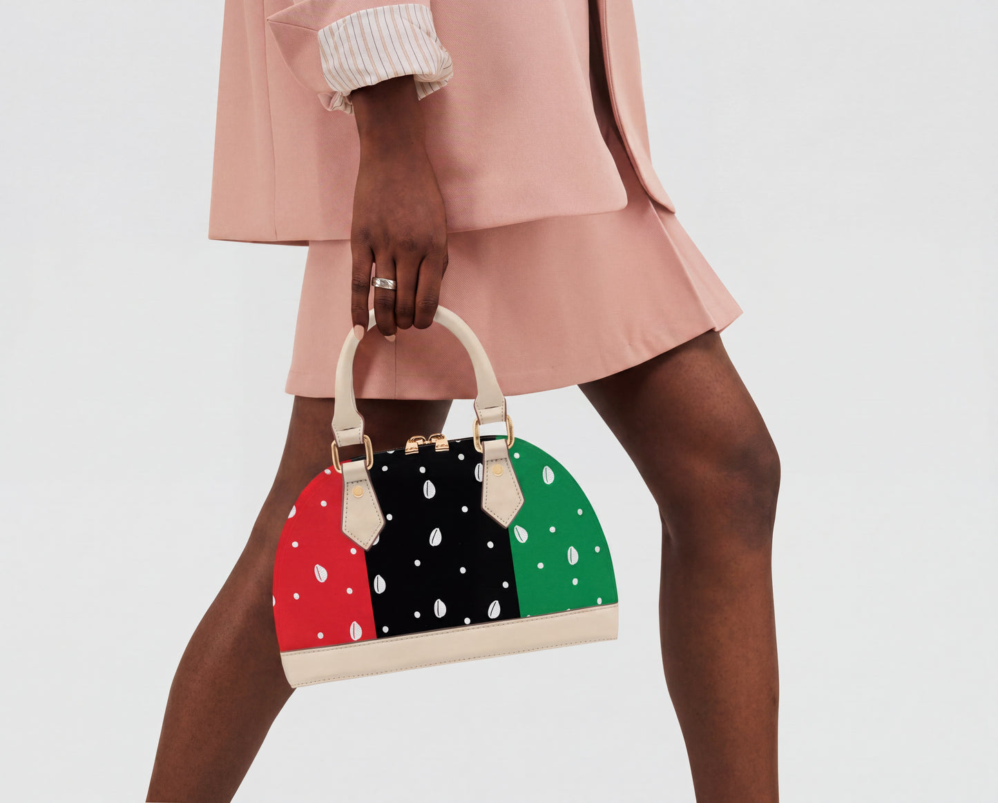 A person wearing a pink outfit and holding a colorful polka dot handbag.