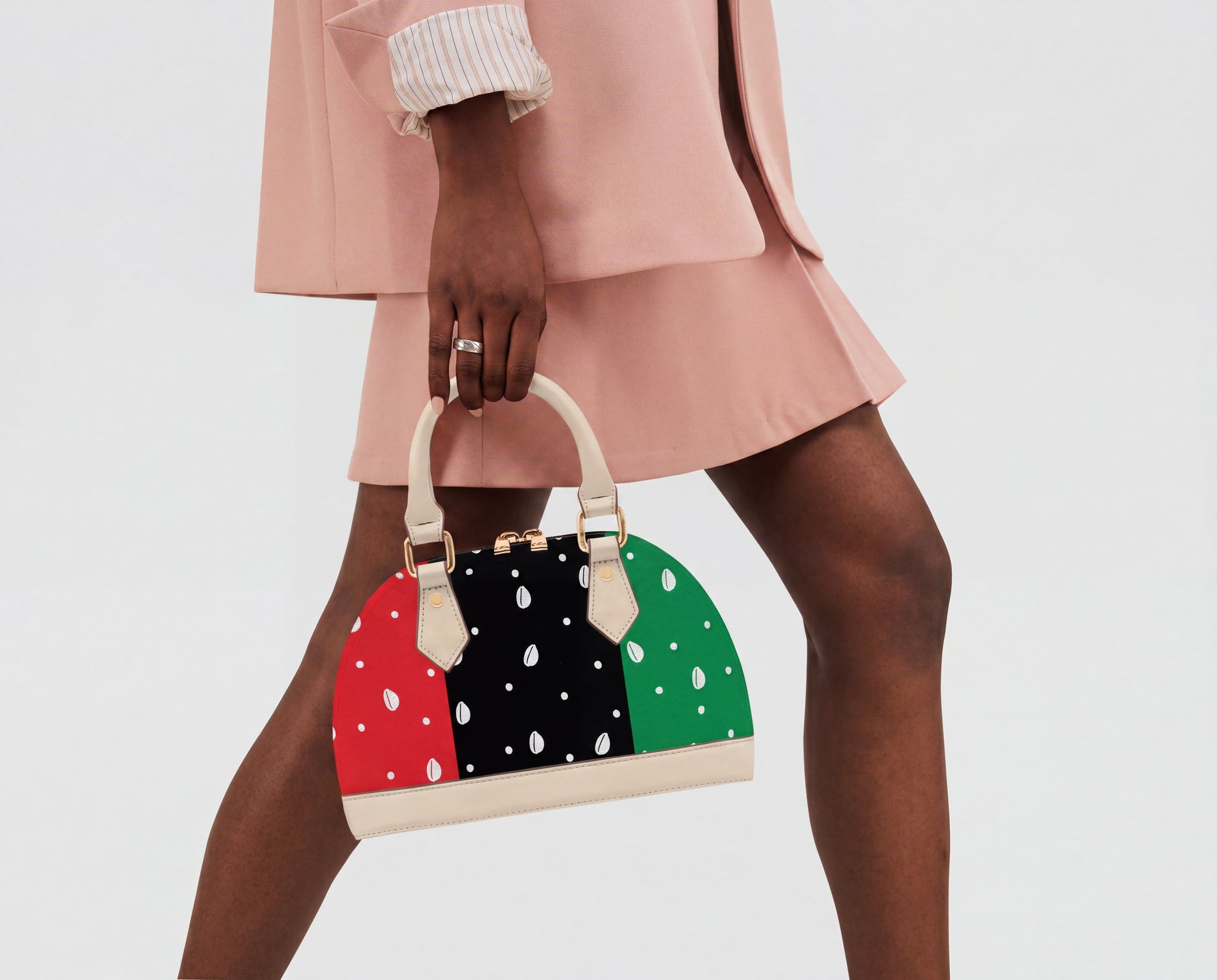 A person wearing a pink outfit and holding a colorful polka dot handbag.