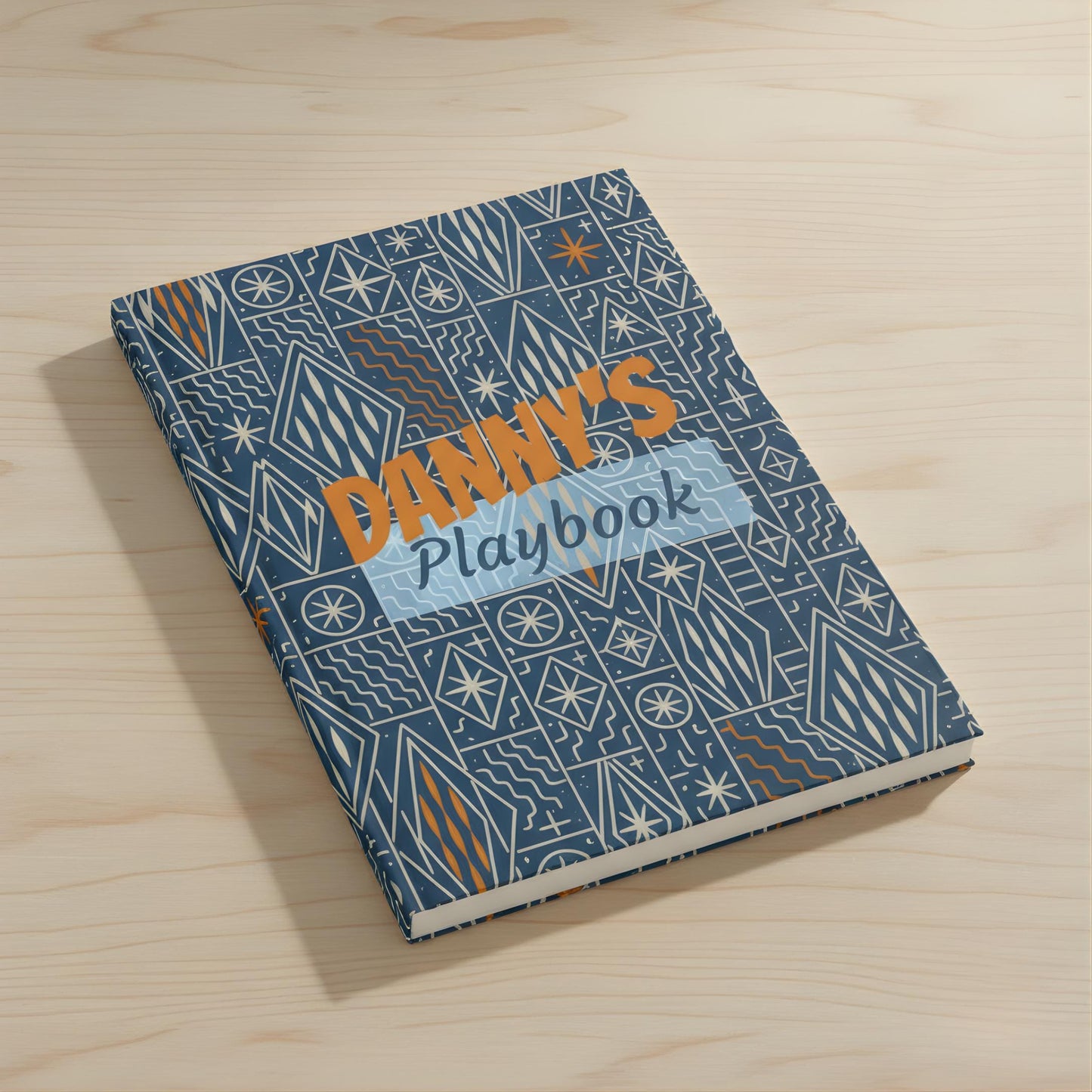 a book titled "DANY'S Playbook" with a patterned cover, resting on a wooden surface.