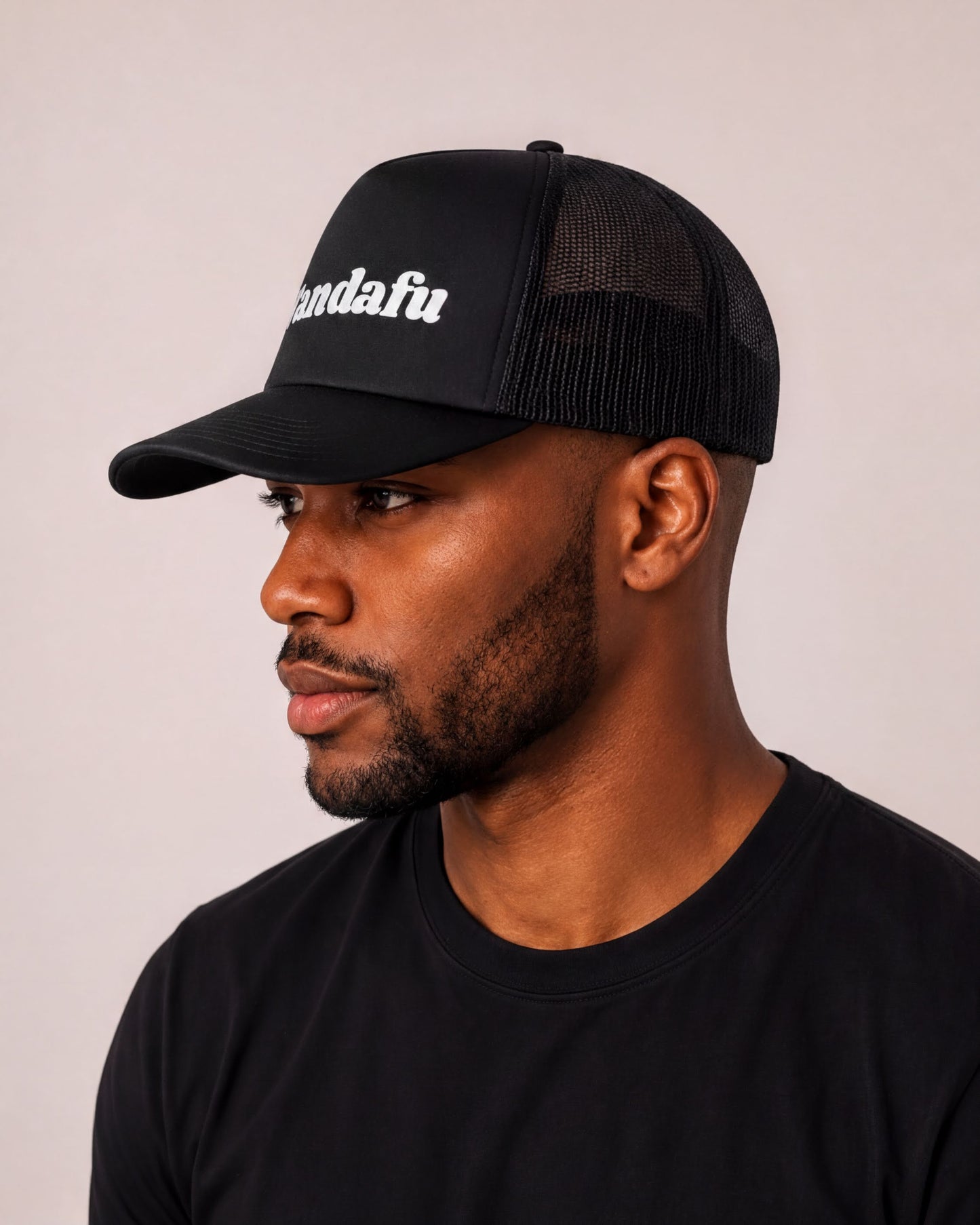 A man wearing a black baseball cap with the word "landau" printed on it.