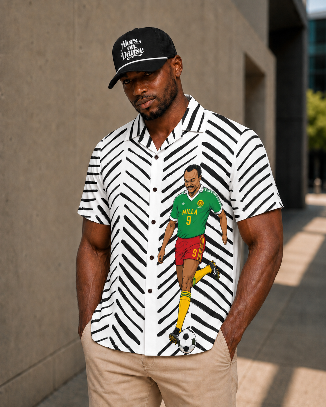 A man wearing a black baseball cap and a shirt with a soccer player graphic stands in front of a building.