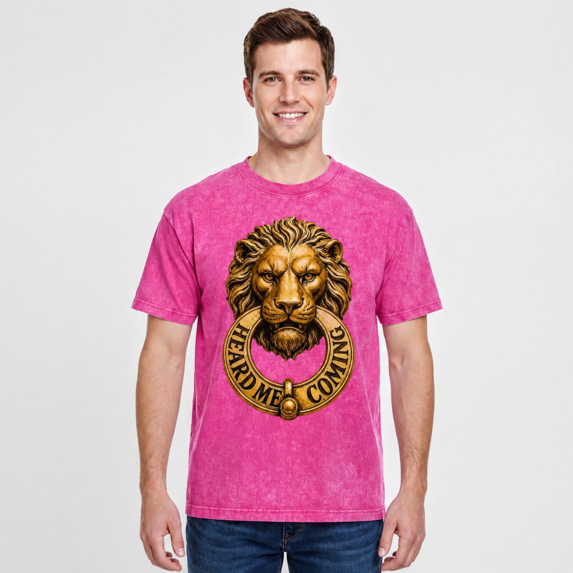 A man wearing a pink t-shirt with a lion's head design and the text "HEARD M' COMING" printed on it.