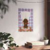 a wall with a framed artwork depicting a person's face, surrounded by a checkered pattern. The artwork is hanging on a white wall, and there are two potted plants in the foreground, one on the left and one on the right. Additionally, there are two books on a wooden surface, one on the left and one on the right.