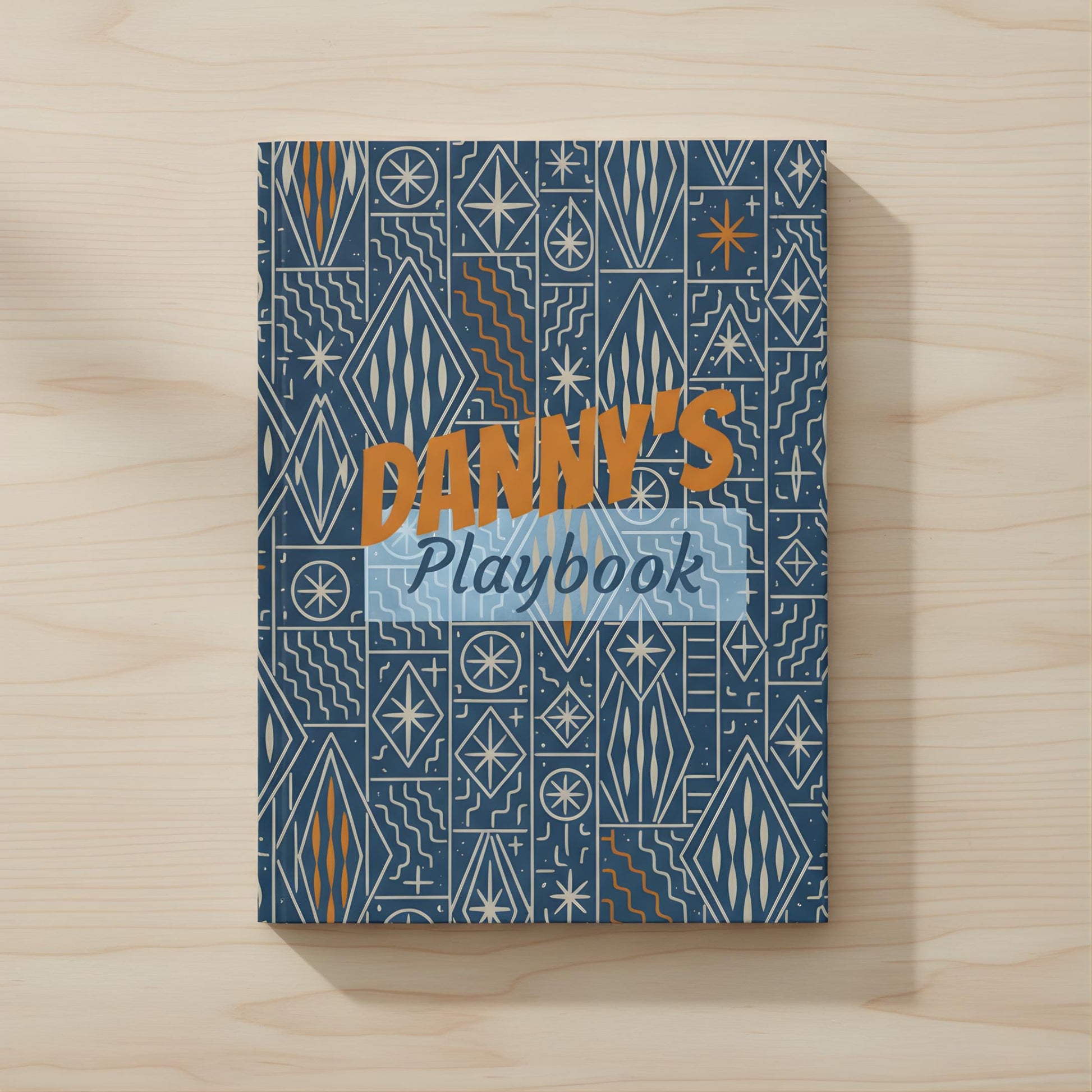 The image is a book cover with a geometric pattern in shades of blue and orange. The title "DANY'S Playbook" is prominently displayed in the center of the cover.