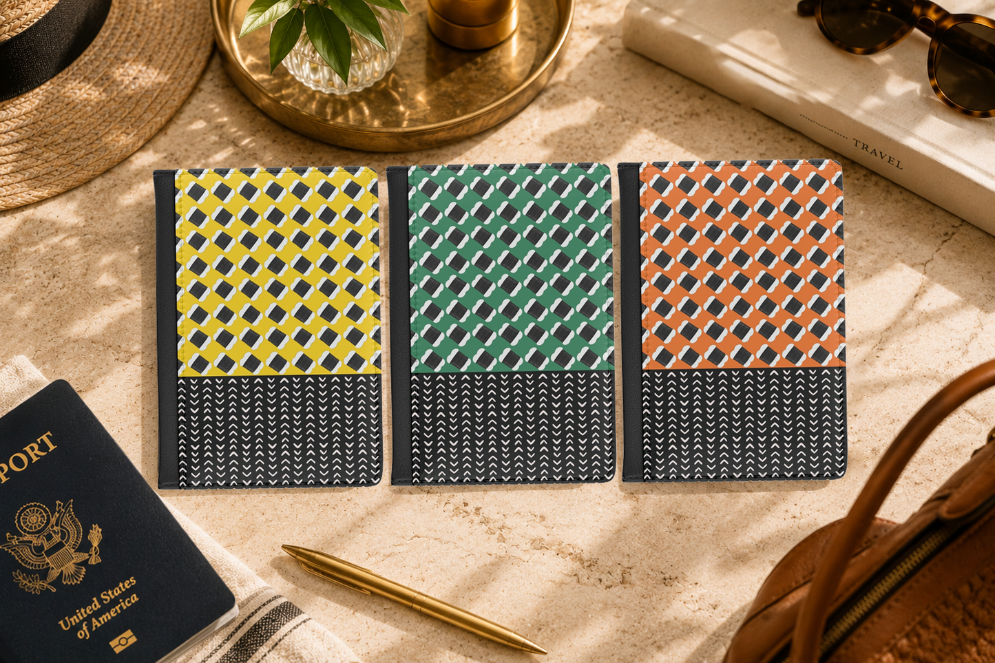 three colorful notebooks with unique geometric patterns, placed on a table alongside a passport, a pen, and a hat.
