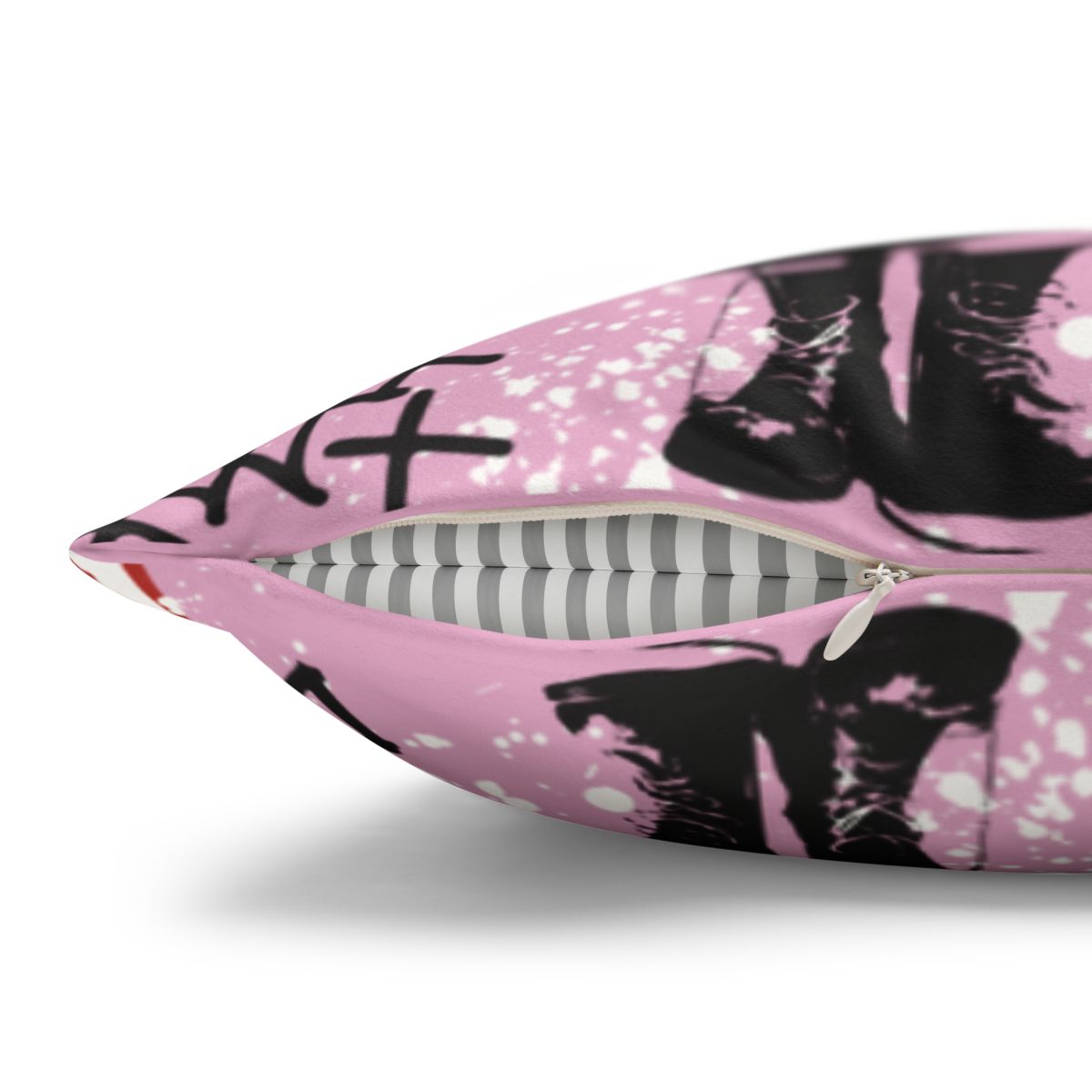A close-up view of a pink pillow with a black and white pattern of silhouettes, including a pair of boots.