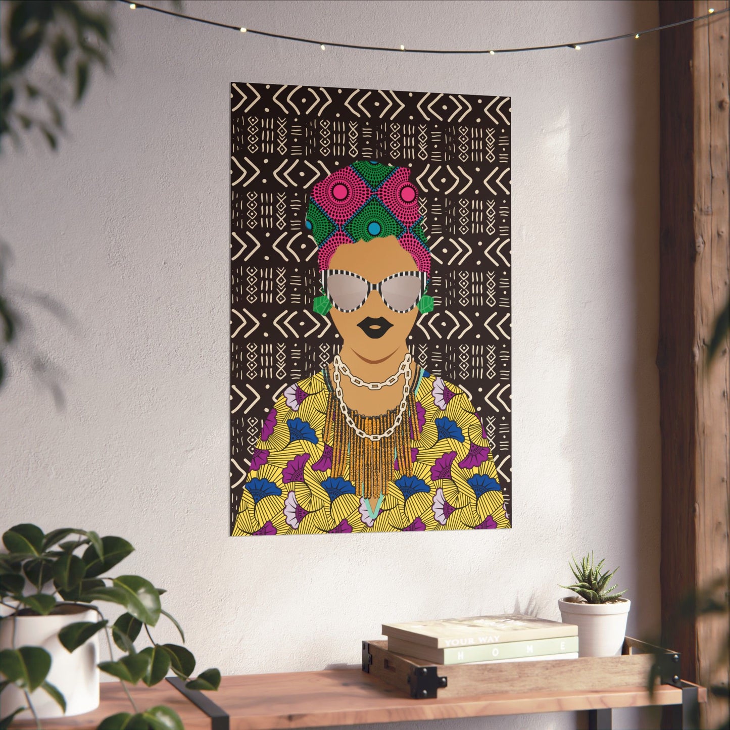 a colorful and vibrant poster of a woman with a head wrap, displayed on a wall in a room with a wooden table and potted plants.