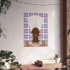 a wall with a framed picture of a person's face, which appears to be a portrait. The wall is decorated with a potted plant and a small table with a book and a plant on it.